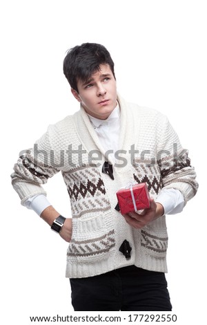 young thoughtful man in casual winter clothing holding gift. isolated on white