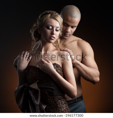 young sensual caucasian woman in dress made of coffee beans and black man standing over gradient orange background
