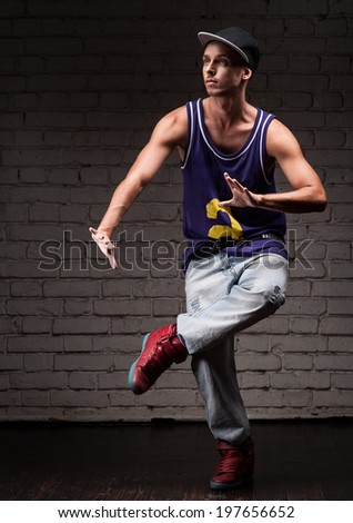 young caucasian male hip-hop dancer showing some moves over brick wall background