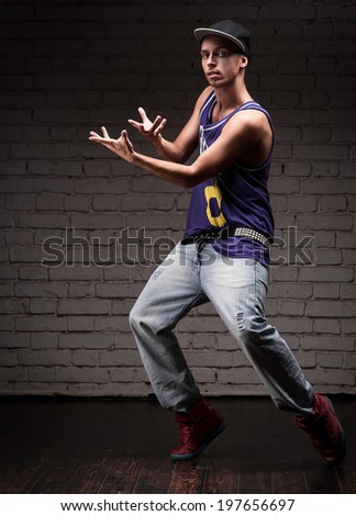 young caucasian male hip-hop dancer showing some moves over brick wall background