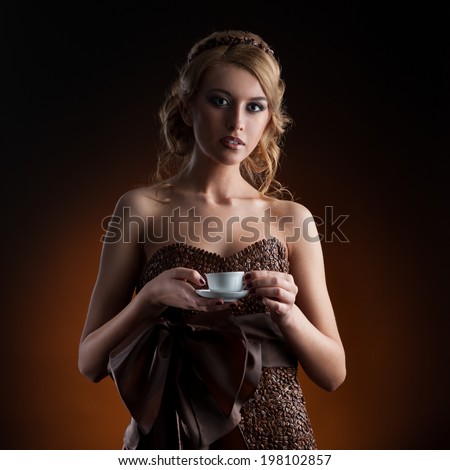 young sensual caucasian woman in dress made of coffee beans standing over gradient orange background