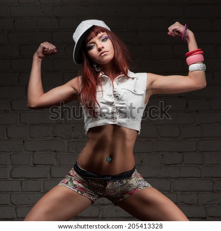 young caucasian hip-hop dancer girl showing some moves over brick wall background