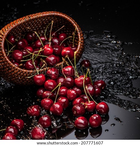 fresh red cherry falling from brown basket over water wave