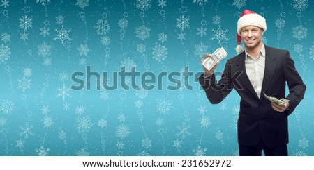 smiling young business man in santa hat holding money over winter snowflakes background