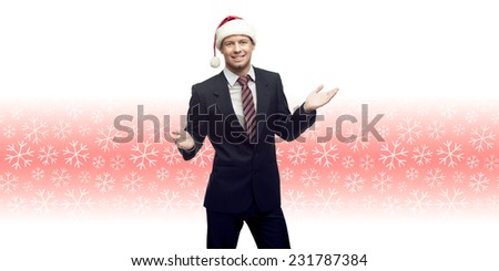 smiling young business man in santa hat showing empty space over winter snowflakes background