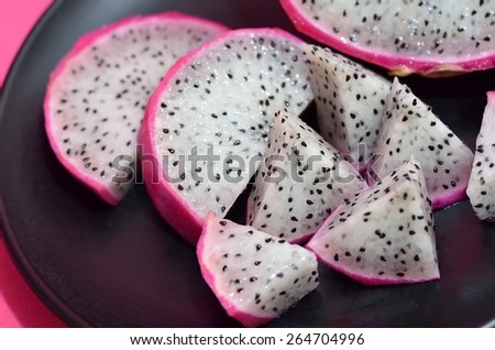 closeup of a dragon fruit cut into pieces, in a black plate