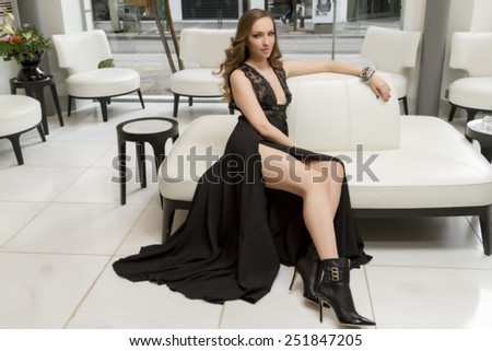 Glamourous portrait of the young beautiful woman in leather boots and stylish Dress. Trend fashion look. Beauty Fashion Model sitting in a trendy shoes.