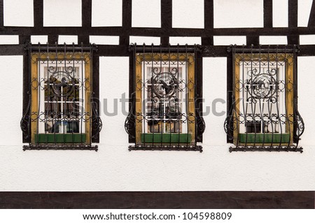 Windows on timber framed house with ornate metal bars
