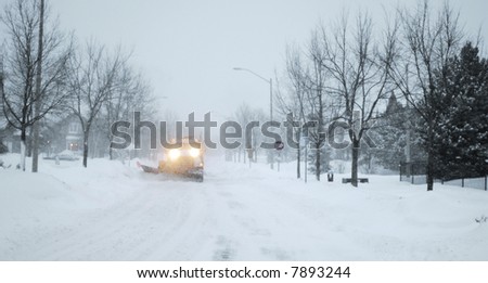 Snowed street with snow-plowing truck