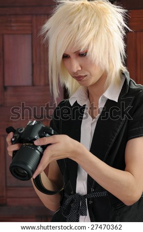 Young man with bleached hair inspecting a camera