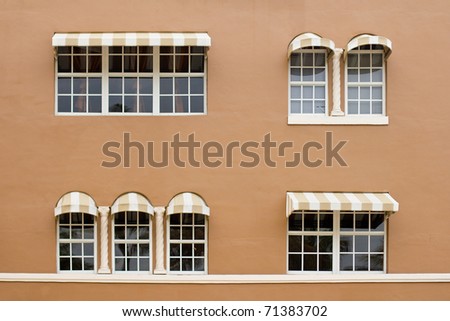 Windows with awnings on a brown wall