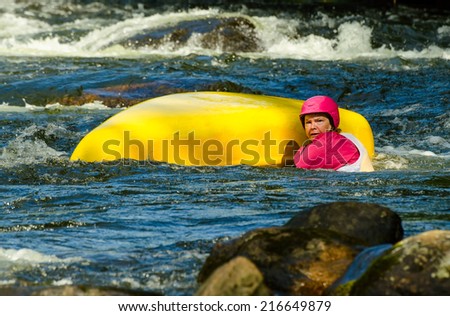 MINDEN, ONTARIO - SEPTEMBER 6, 2014: An unidentified contestant swimms beside an upturned canoe  at 2014 Open Canoe Slalom Race at Gull River in Minden, Ontario, Canada.