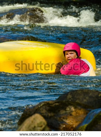 MINDEN, ONTARIO - SEPTEMBER 6, 2014: An unidentified contestant swims beside an upturned canoe  at 2014 Open Canoe Slalom Race at Gull River in Minden, Ontario, Canada.