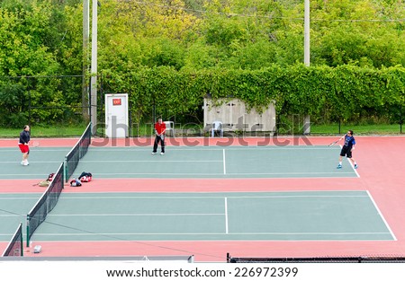 NEWMARKET, ONTARIO - SEPT. 13, 2014: Group of senior citizens playing tennis on an asphalt court.