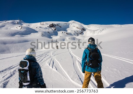 Snowboarders waiting for their friend during free-ride off-piste run on snowy mountain