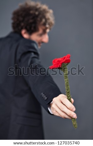 Boy with glasses and jacket is donating a fabric red rose