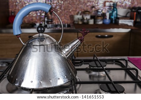 steel kettle with a bird shaped cap is on an off stove in a modern kitchen
