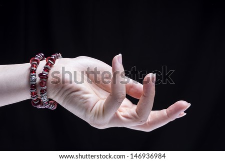 Female hand, isolated on black background, is wearing some ornaments