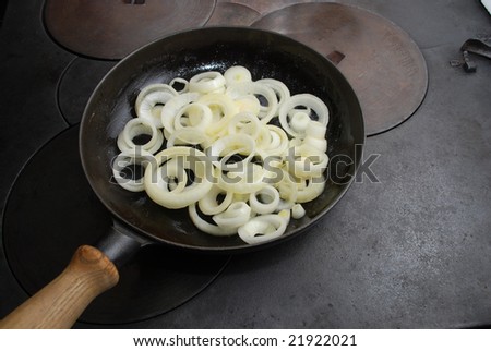 Fresh onions in a frying pan on a wood stove