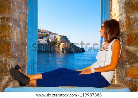 Young woman relaxing by window frame and looking view  in Santorini island Greece