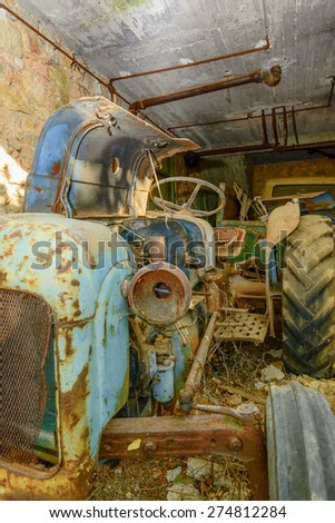 Old and abandoned Tractor in Garage at fall with leaves around