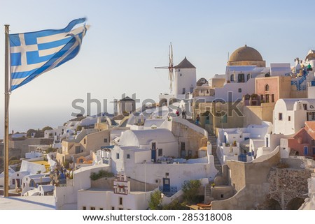 Greece Santorini island in Cyclades, Greek flag waving in Oia where the sunseters wait for one of the most famous sunsets in the world