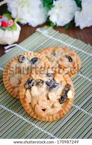 Homemade tart with dried cashew nut and dried raisins on bamboo mat background