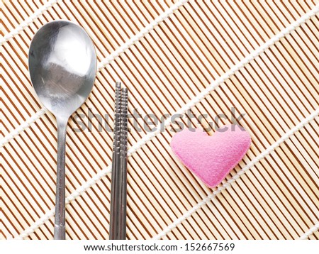 Asian spoon and chopsticks setting on bamboo mat with little heart, Korean style