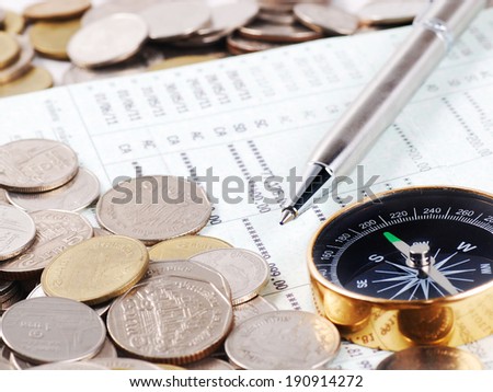 Pen and compass on bank account book with coins background