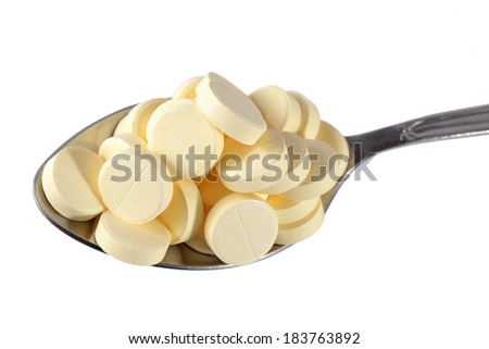 Spoon full of pills on a white background
