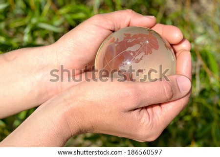 Globe in the palm of hands on green background.