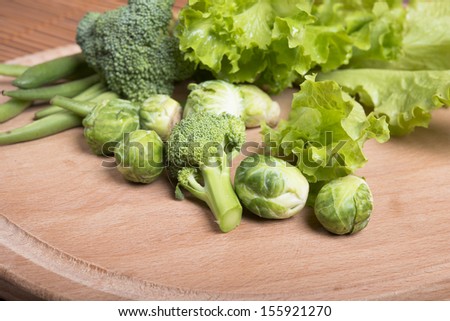 raw asparagus beans, brussels sprouts, broccoli and lettuce on  wooden board.