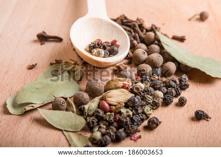 wood spoon with spices,  bay leaves, cardamon and cloves on wooden board