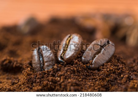 Three coffee beans with ground coffee heap.  Arabic roasted coffee.Coffee beans and  ground coffee on brown background.