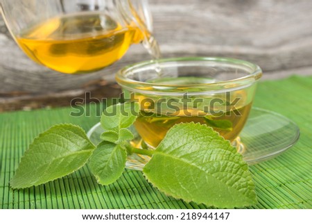 Pouring tea into cup of tea on green bamboo mat