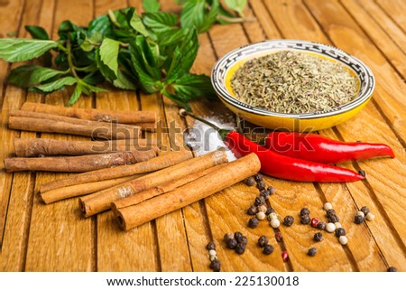 spices on cup, mint, cinnamon and pepper  on  wooden table background