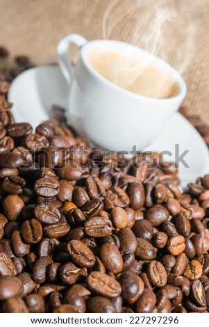 cup of coffee with a smoke and roasted coffee beans on burlap