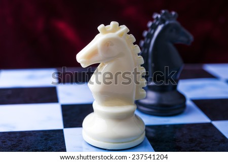 Black and white horses. Black and white chess pieces on blue board