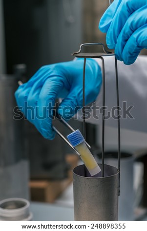 Gloved hand hold the tube with cell suspension for cryopreservation. A Liquid Nitrogen bank containing suspension of stem cells. Cell culture for the biomedical diagnostic.