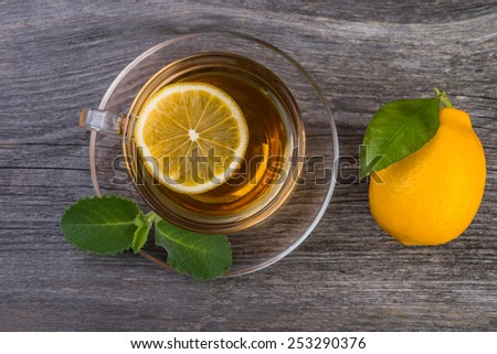 Overview of  cup of tea with mint and lemon on wooden table