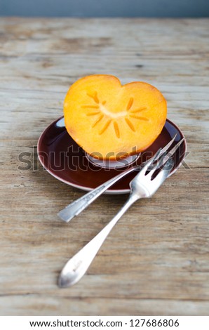 Heart Shaped Persimmon On Brown Saucer With Silver Dessert Forks