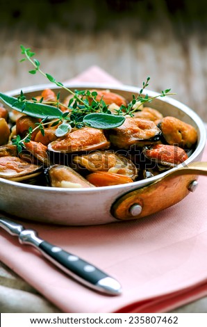 Mussels in cream and garlic sauce with provencal herbs in aluminum saucepan, shallow DOF, selective focus