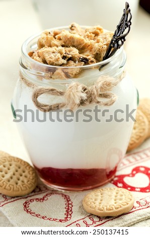 Light yogurt with wholewheat cookie crumbs and berry jam on the heart decorated cloth. Shallow DOF, selective focus