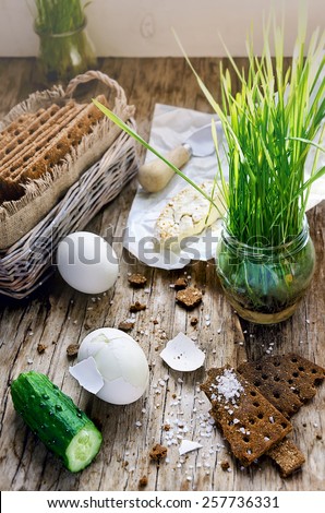 Hard boiled eggs, cucumber, camembert cheese, germinated seeds of grass and wholegrain crisps on the vintage wooden table