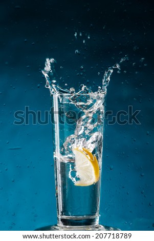Lemon splashing into a glass of water