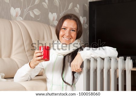 smiling woman  with red cup near oil heater