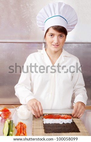 Cook woman making  japanese sushi rolls in kitchen