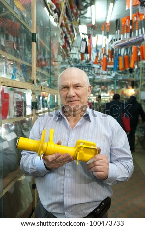 mature man holds  shock absorber  in  auto parts store
