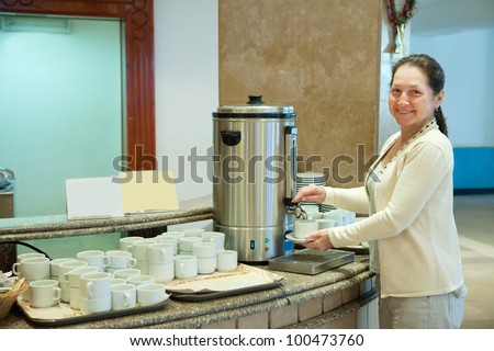 Woman pours tea from  electric water boiler