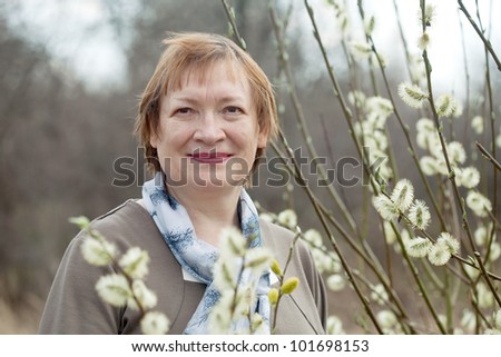 Smiling senior woman  in spring willow twig with buds outdoor